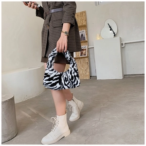 Détail du sac à main en peluche zébré associé à un blazer et des bottes pour un look chic