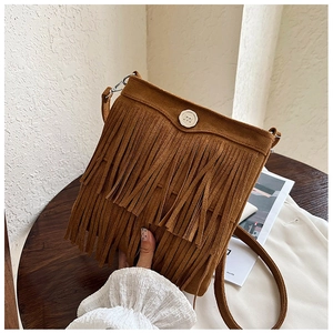 Detailed close-up of brown fringe crossbody bag with metallic circular buckle