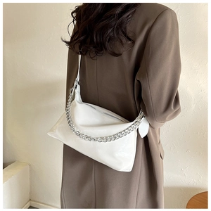 Détail d'un sac à bandoulière blanc brillant avec une grosse chaîne en métal argenté