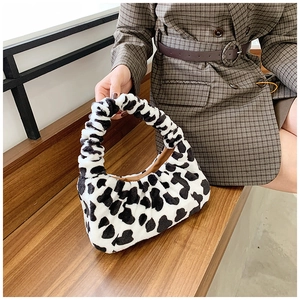 Détail d'un sac en peluche à motif zébré avec poignée froncée sur fond en bois