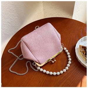 Detailed view of pink tweed bag featuring gold metal frame and elegant pearl handle