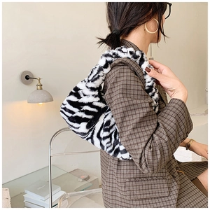 Sac bandoulière chic en peluche à motif zébré porté par un mannequin en intérieur