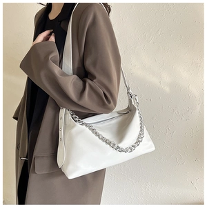 Détail d'un sac à bandoulière blanc en cuir avec grosses chaînes argentées et rivets