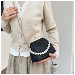 Detail view of black sequin frame bag with pearl handle and golden chain shoulder strap