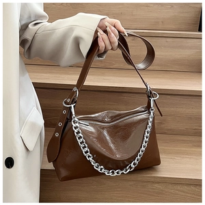 Détail d'un sac à bandoulière marron brillant avec chaîne argentée et large sangle