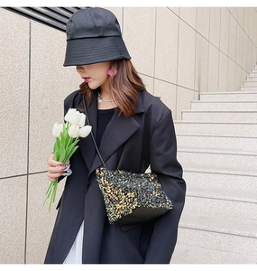 Detail of sequin crossbody bag with black and gold patterns and elegant metal chain strap