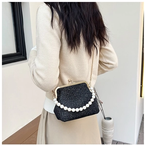 Close-up of black glitter crossbody bag featuring vintage gold clasp and pearl handle