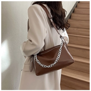 Sac baguette en cuir marron avec chaîne argentée porté avec une tenue élégante