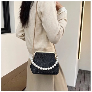Close-up of black glitter bag with vintage gold clasp and large pearl handle detail