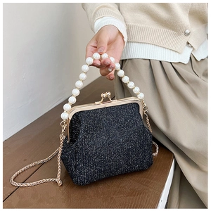 Close-up of black glitter evening bag with pearl handle and golden metal frame detail