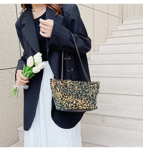Detail of sequined tote bag with shimmering scales and dual metal chain straps
