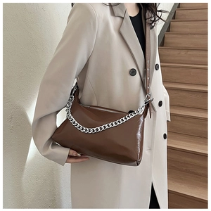Détail d'un sac porté épaule en cuir marron foncé brillant avec chaîne en argent