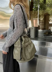 Close-up of olive green nylon bucket bag with drawstring closure and side pocket