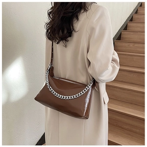 Détail du sac à bandoulière marron foncé brillant avec chaîne argentée et fermeture
