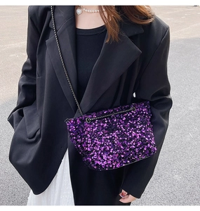 Close-up of a purple sequined crossbody bag with a slim black metal chain strap