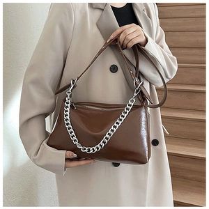 Détail d'un sac en cuir ciré marron foncé avec une grosse chaîne en métal argenté
