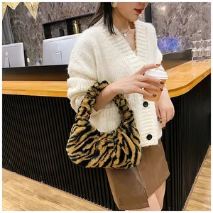 Sac bandoulière tendance en fausse fourrure à motif tigre dans un décor de café chaleureux