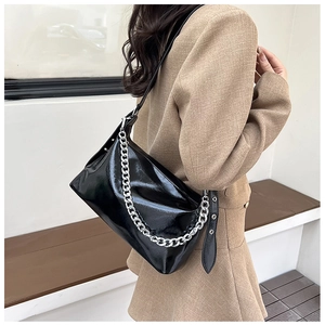 Détail du sac à bandoulière en cuir verni noir avec chaîne argentée et sangle réglable