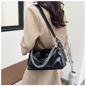 Détail du sac à bandoulière noir brillant avec chaîne argentée et design minimaliste en cuir