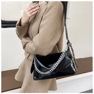 Gros plan du sac porté épaule noir verni avec grosse chaîne argentée sur un mannequin
