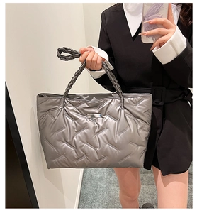 Detail of silver quilted tote bag with braided handles and metallic finish