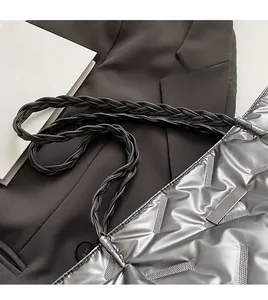 Detail of silver quilted shoulder bag featuring durable black woven straps and metallic finish