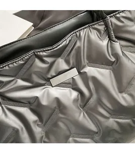Close-up of silver quilted tote bag with metallic sheen and rectangular metal detail