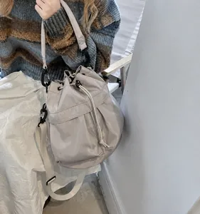 Detail of grey nylon bucket bag showing drawstring closure and outdoor style webbing strap