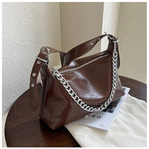 Détail d'un sac à main marron foncé avec chaîne métallique et bandoulière réglable