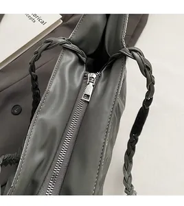 Detail of silver zipper closure and woven handle on deep grey-green tote bag