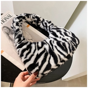 Détail de la texture d'un sac à main en fausse fourrure zébrée sur une table noire