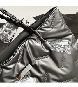 Detail of silver puffer tote with quilted texture and hand-stitched smooth leather handles
