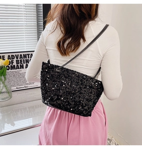 Detail of black sequined crossbody bag with fine metal chain straps on model