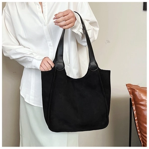 Detailed view of a large black plush tote bag featuring elegant leather long handles