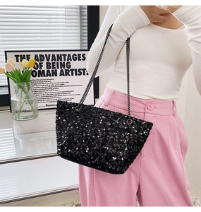 Detail shot of a black sequin tote bag with gunmetal chain straps on a model outfit