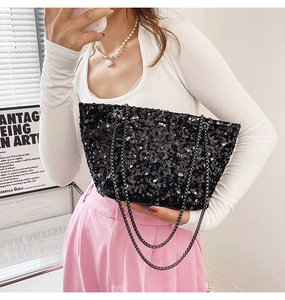 Detail of black sequined shoulder bag featuring glossy texture and a metallic chain strap