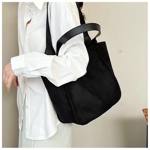 Detail of the large black plush tote bag showing the textured fabric and long leather straps