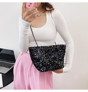 Close-up of iridescent purple sequins on a black trapezoid chain bag with metal strap