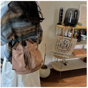 Detail of a brown nylon drawstring bucket bag with pleated design and silk finish
