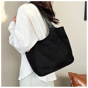 Side view of large black plush tote bag showing soft texture and wide shoulder strap comfort