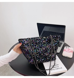 Close-up of black sequin tote bag with dual metal chain straps on office desk