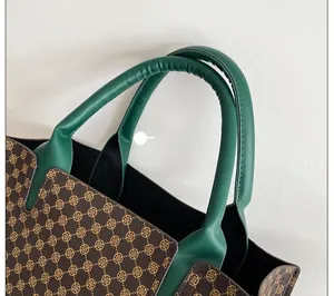 Close-up of green leather handle and brown vintage clover pattern on a tote bag