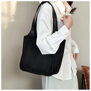 Detail view of large black nylon tote bag on shoulder with casual autumn style