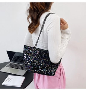 Detail of sequin shoulder bag with dual chain straps worn by model in urban setting