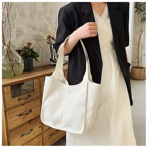 Minimalist white nylon tote bag with wide shoulder strap used in a casual setting