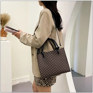 Detailed side view of a vintage monogram tote bag featuring leather straps and golden feet
