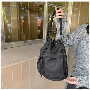 Detailed view of black nylon bucket bag with drawstring closure and metal zipper pocket