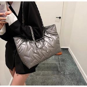 Detail of silver quilted tote bag featuring braided rope handles and metallic texture