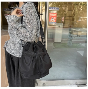 Detail of black nylon drawstring bucket bag with adjustable wide fabric shoulder strap