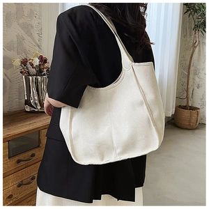 Minimalist beige tote bag shown on shoulder in a stylish home office setting